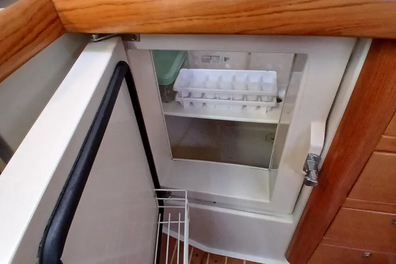 Slide: The Image of Open refrigerator in 2003 Catalina 350 yacht, featuring ice tray and wooden interior. - 12