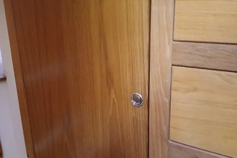 Slide: The Image of Wooden interior paneling of a 2003 Catalina 350 yacht, featuring a sleek metal handle. - 24