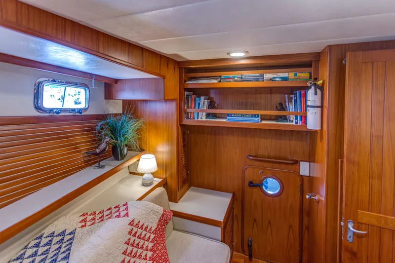 Slide: The Image of Cozy 2007 Krogen 44' Widebody cabin with wooden interior, bookshelves, and nautical decor. - 10