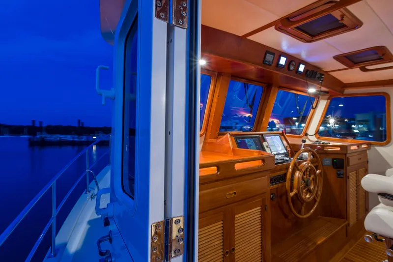 Slide: The Image of 2007 Krogen 44' Widebody yacht interior with wooden helm and navigation equipment at dusk. - 21