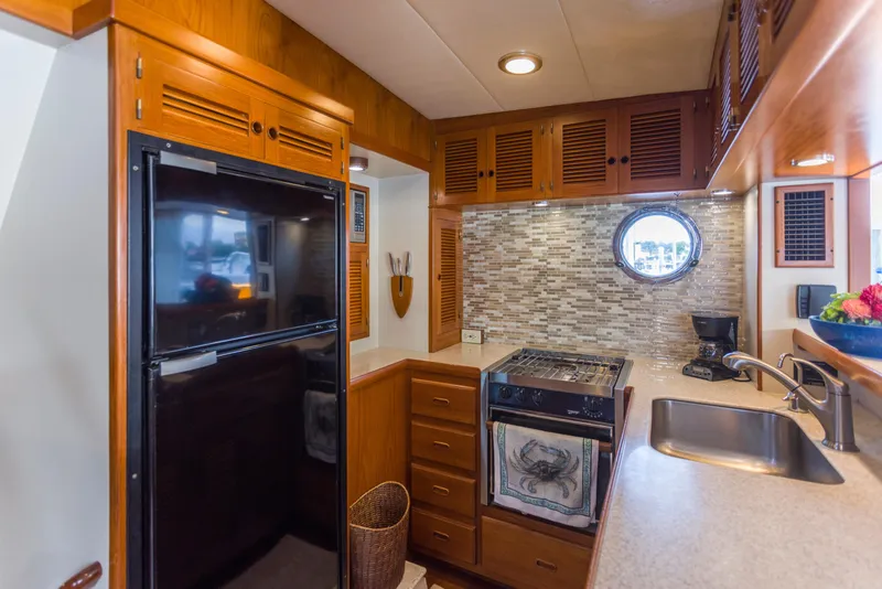Slide: The Image of 2007 Krogen 44' Widebody yacht kitchen with wood cabinetry, porthole, and modern appliances. - 7