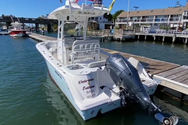 Slide: The Image of 2024 Sea Fox 228 Commander boat docked, featuring a powerful outboard motor. - 2