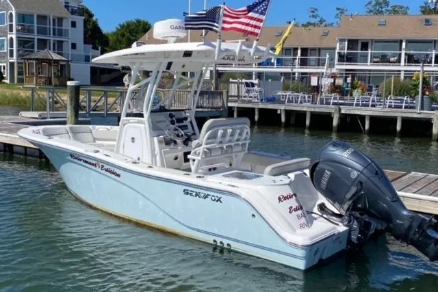 Slide: The Image of 2024 Sea Fox 228 Commander boat docked, featuring American flags and waterfront homes in the background. - 1