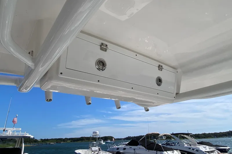 Slide: The Image of 2024 Sea Fox 228 Commander boat storage compartment with rod holders, docked on a sunny day. - 11