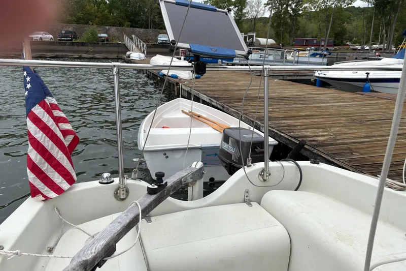 Slide: The Image of Sonic 23 sailboat from 1983 docked, featuring an American flag and Tohatsu motor. - 10