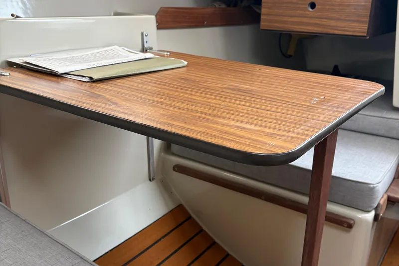 Slide: The Image of Interior of 1983 Sonic 23 boat with wooden table and cushioned seating. - 18