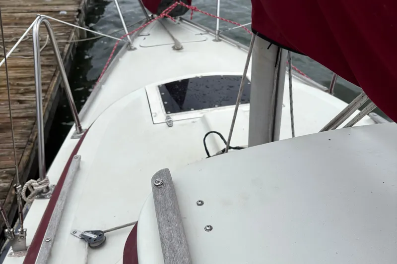 Slide: The Image of 1983 Sonic 23 sailboat docked, featuring a clean deck and red sail cover. - 2