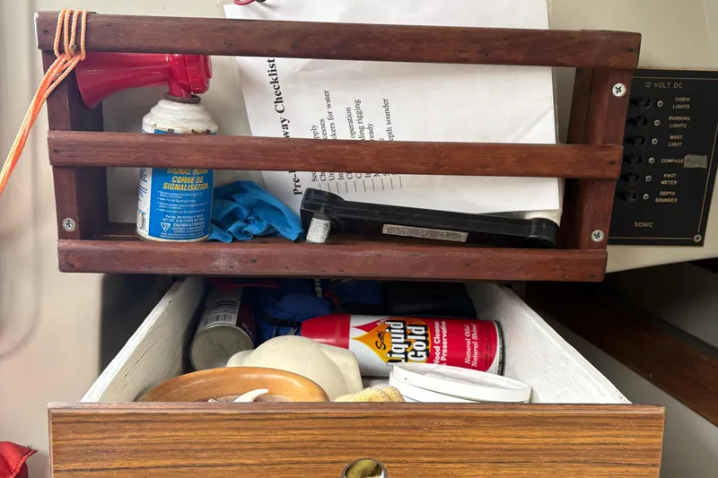 Slide: The Image of Wooden shelf with checklist, air horn, and cleaning supplies on a 1983 Sonic 23 boat. - 20