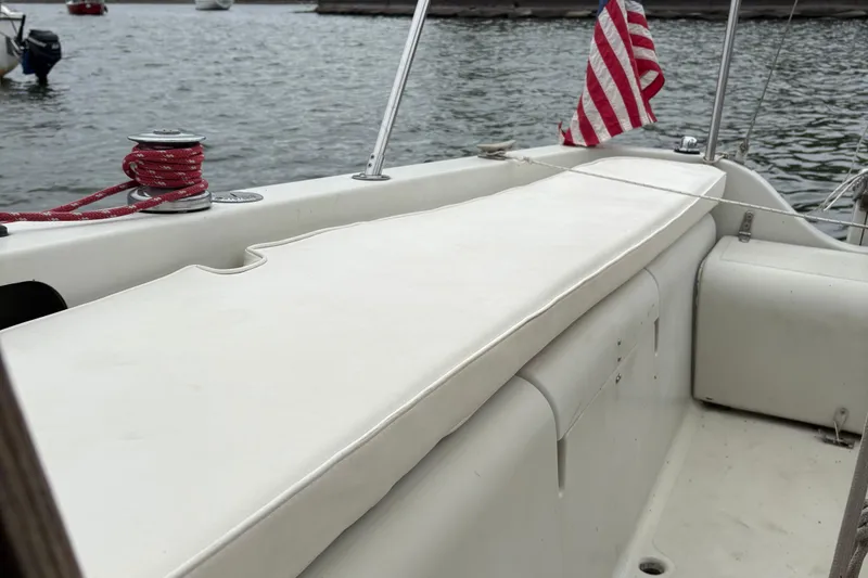 Slide: The Image of 1983 Sonic 23 sailboat cockpit with American flag and winch, docked on calm water. - 29