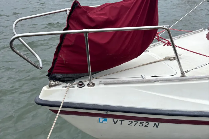 Slide: The Image of 1983 Sonic 23 sailboat with maroon cover, docked on calm water. - 6