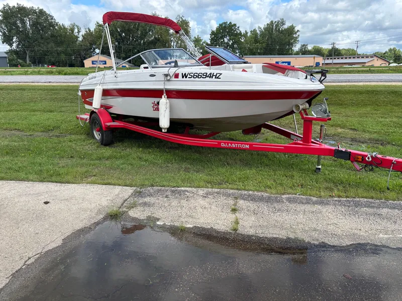 Slide: The Image of 2013 Glastron 205 MXSF boat on red trailer, parked on grass. - 15