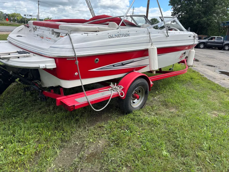 Slide: The Image of 2013 Glastron 205 MXSF boat on red trailer, parked on grass. - 16