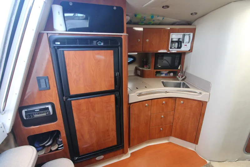 Slide: The Image of 2004 Larson 370 Cabrio yacht interior kitchen with wood cabinets, fridge, and appliances. - 23