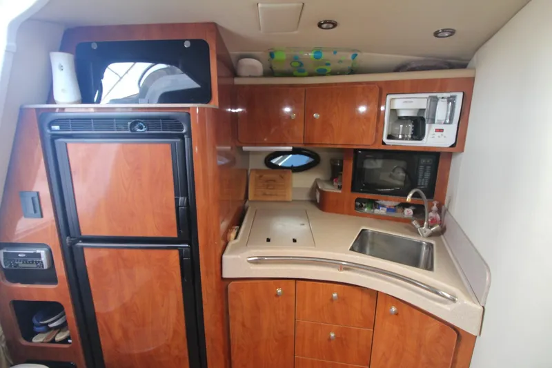 Slide: The Image of 2004 Larson 370 Cabrio yacht kitchen with wood cabinets, sink, microwave, and refrigerator. - 26