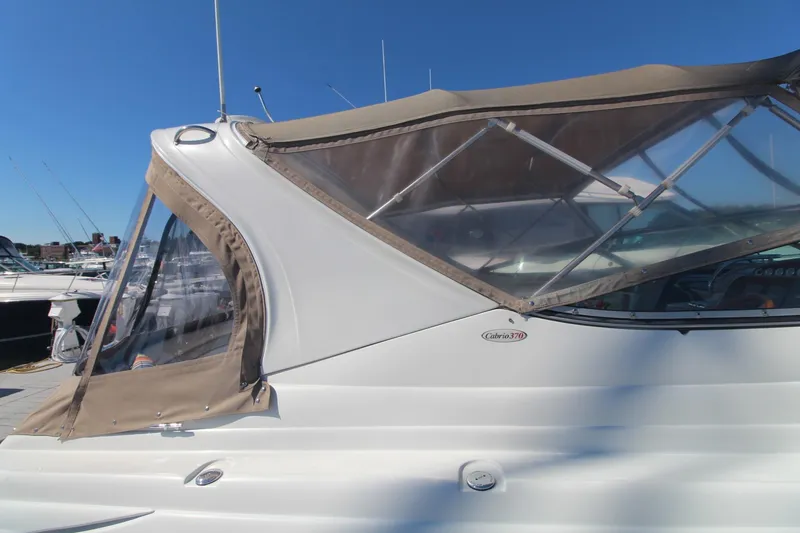 Slide: The Image of 2004 Larson 370 Cabrio boat with beige canopy docked under clear blue sky. - 5