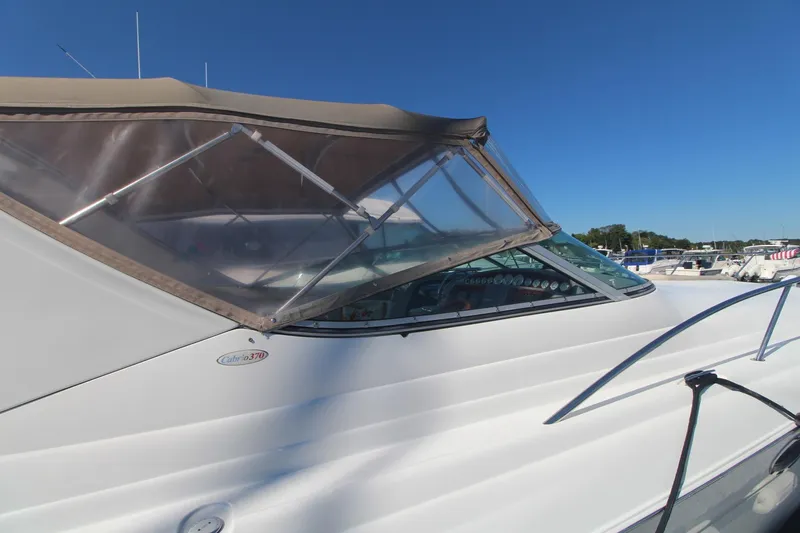 Slide: The Image of 2004 Larson 370 Cabrio boat with canopy, docked under clear blue sky. - 6