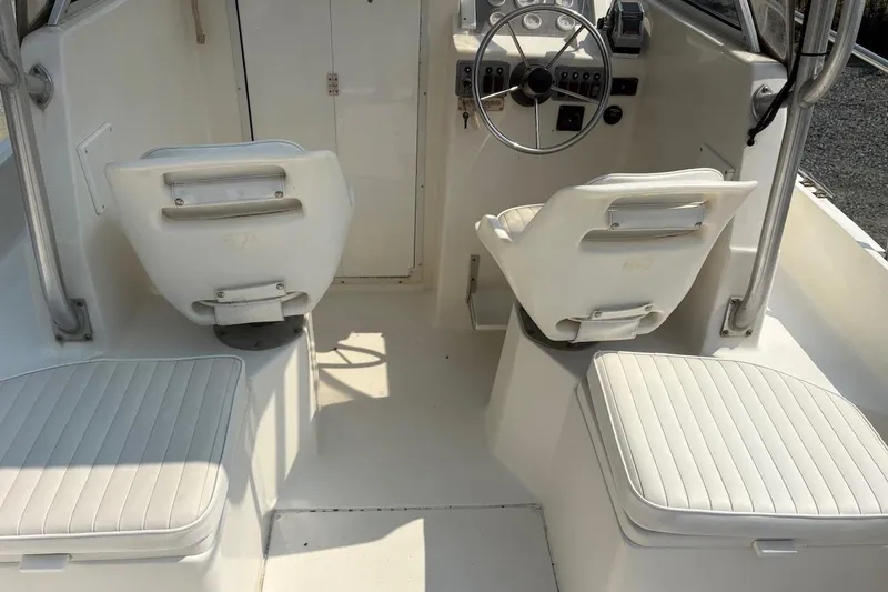 Slide: The Image of 1995 Baha Cruisers 240 Walkaround boat interior with white seating and steering wheel. - 11