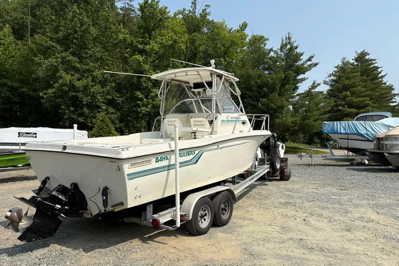 Slide: The Image of 1995 Baha Cruisers 240 Walkaround boat on trailer, surrounded by trees and other boats. - 2