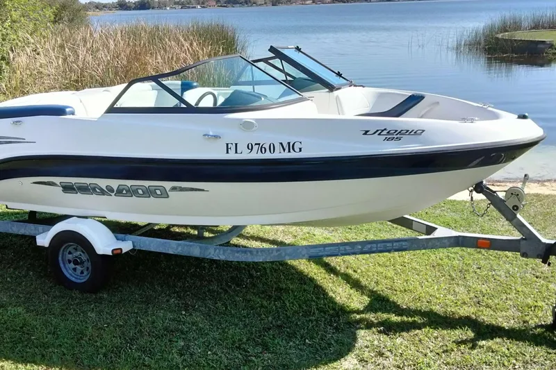 Slide: The Image of 2003 Sea-Doo Utopia 185 boat on trailer by a lake. - 1
