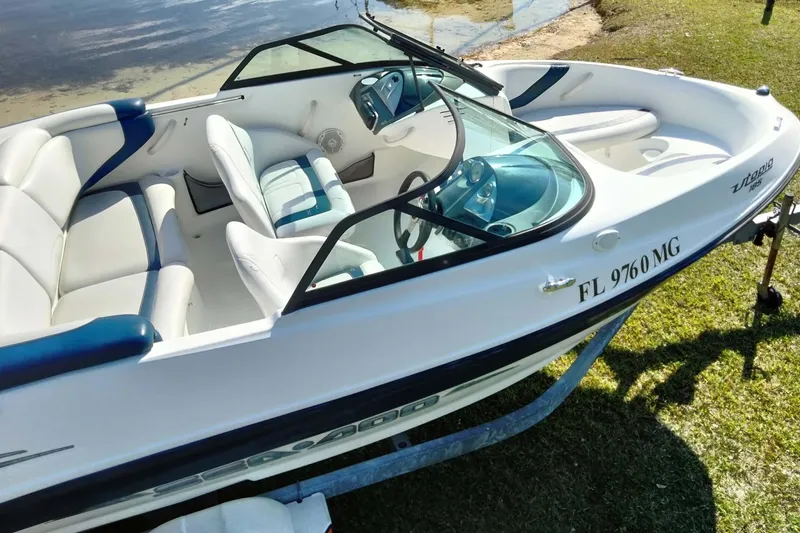 Slide: The Image of 2003 Sea-Doo Utopia 185 boat with white and blue interior, parked on grass. - 10