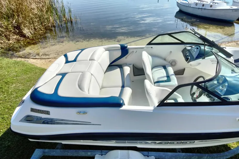 Slide: The Image of 2003 Sea-Doo Utopia 185 boat with white and blue interior, docked by a lake. - 11
