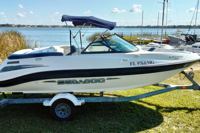 Slide: The Image of 2003 Sea-Doo Utopia 185 boat on trailer by a lake, under a clear sky. - 24