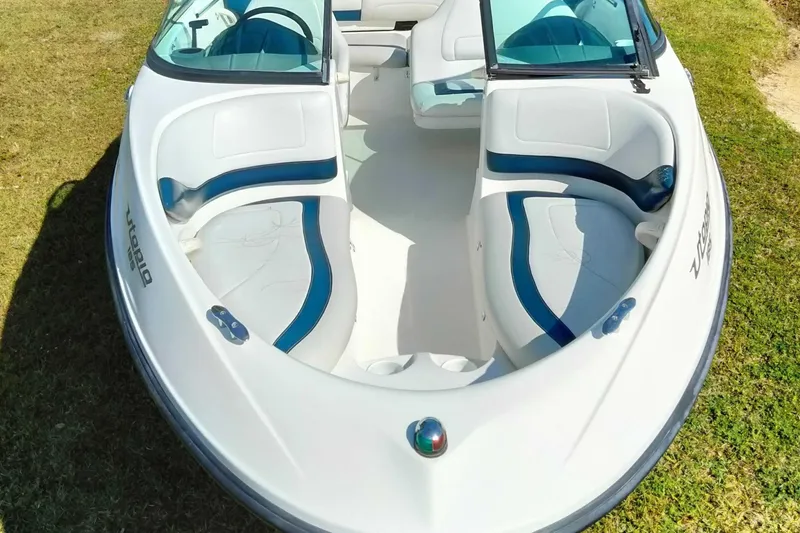 Slide: The Image of 2003 Sea-Doo Utopia 185 boat interior with white and blue seating on grass. - 3