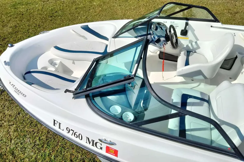 Slide: The Image of 2003 Sea-Doo Utopia 185 boat interior with seating and steering wheel, parked on grass. - 5