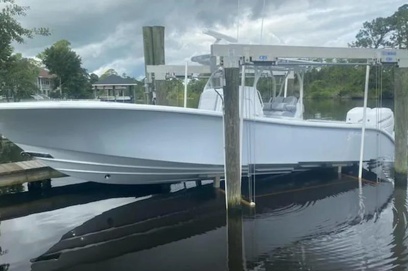 The Image of 2022 Yellowfin 32 boat on lift, docked by a serene waterfront. - 1