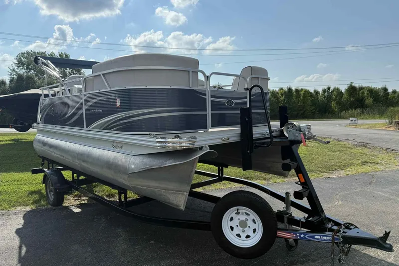 The Image of 2019 Qwest 816 Luxury Series pontoon boat on trailer, parked outdoors under a sunny sky. - 0