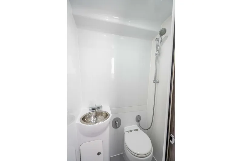 Slide: The Image of 2024 Yellowfin 54 Offshore bathroom with shower, sink, and toilet in sleek white design. - 33