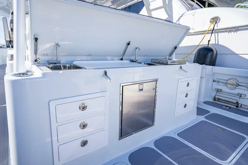Slide: The Image of 2024 Yellowfin 54 Offshore boat kitchen with sink, storage drawers, and stainless steel appliances. - 36