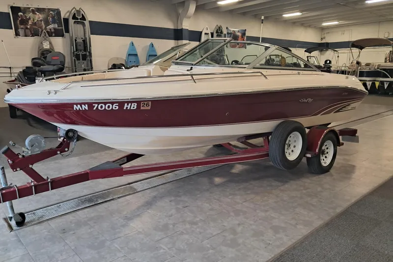 The Image of 1996 Sea Ray 190 Bow Rider boat on trailer in showroom setting. - 1