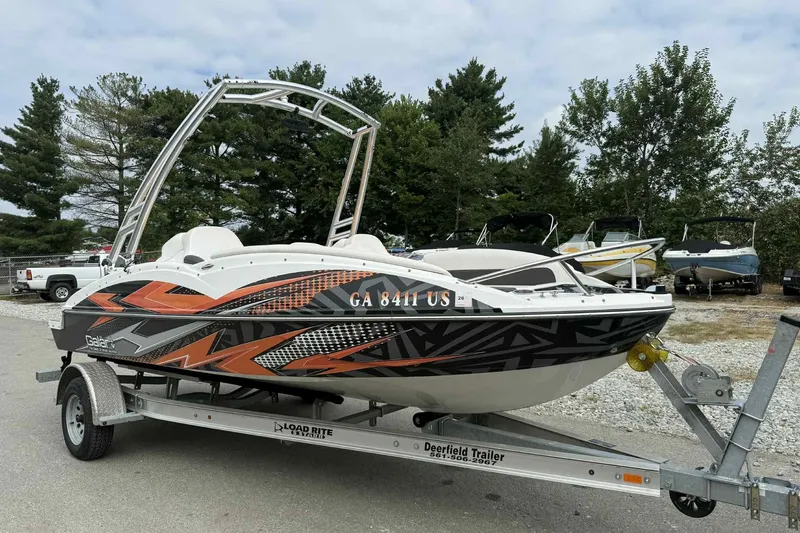 Slide: The Image of 2024 Galar Boats Typhoon with Seadoo GTI SE 155 on trailer, vibrant design, parked outdoors. - 1