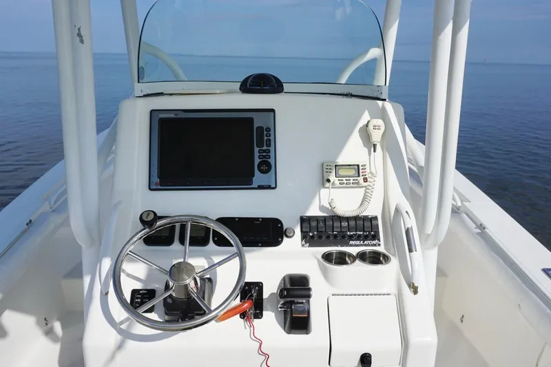 Slide: The Image of 2009 Regulator 24 FS boat console with steering wheel, electronics, and ocean view. - 15