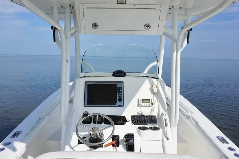 Slide: The Image of 2009 Regulator 24 FS boat console with steering wheel and navigation equipment on calm water. - 16