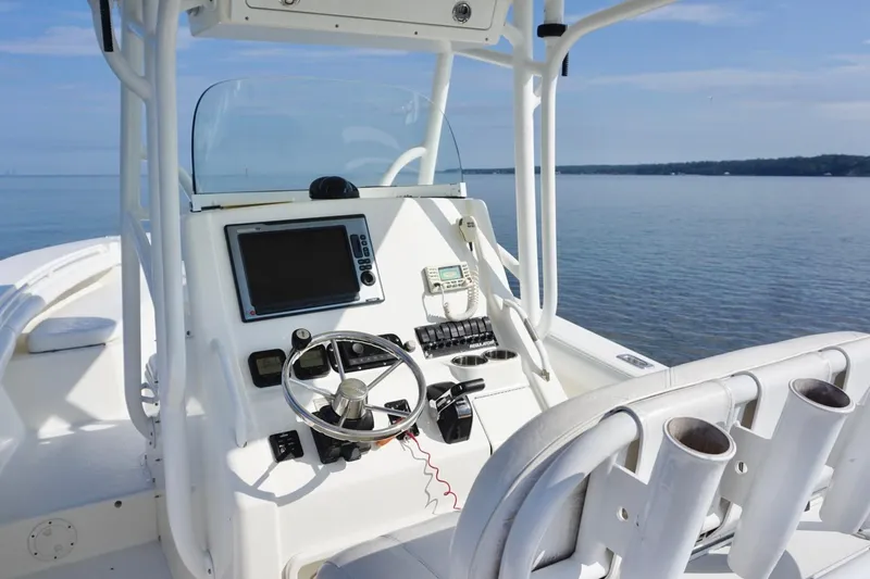 Slide: The Image of 2009 Regulator 24 FS boat cockpit with steering wheel and navigation equipment on calm water. - 18