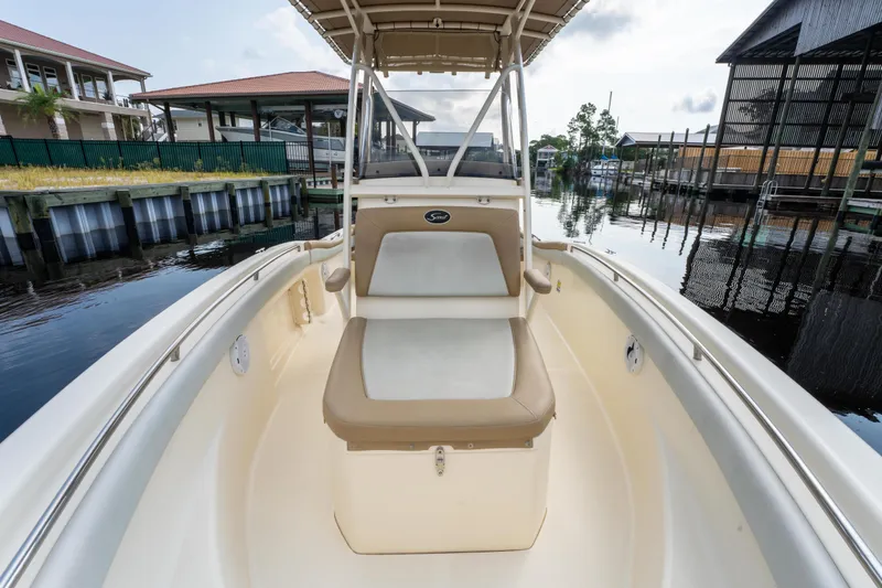 Slide: The Image of 2015 Scout 210 XSF boat interior with seating, docked near waterfront homes. - 11