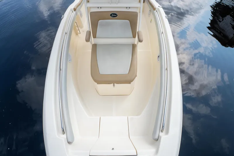 Slide: The Image of 2015 Scout 210 XSF boat interior with cushioned seating, reflecting on calm water. - 15