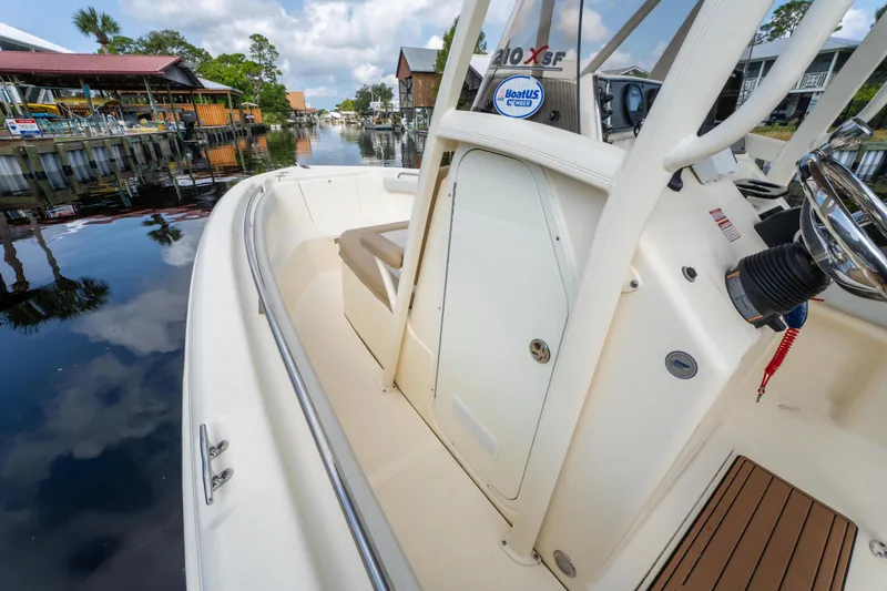 Slide: The Image of 2015 Scout 210 XSF boat docked on a calm waterfront with scenic background. - 17