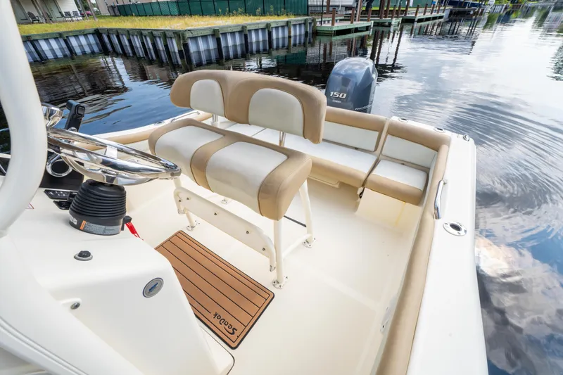 Slide: The Image of 2015 Scout 210 XSF boat interior with seating and steering wheel, docked by calm water. - 22