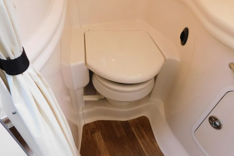 Slide: The Image of 2005 Sea Ray 320 Sundancer bathroom with compact toilet and wooden flooring. - 105