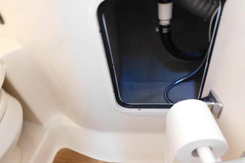 Slide: The Image of 2005 Sea Ray 320 Sundancer bathroom compartment with visible plumbing and toilet paper holder. - 114