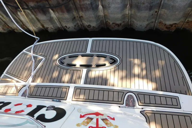 Slide: The Image of 2005 Sea Ray 320 Sundancer swim platform with teak-style decking, docked by a weathered wall. - 19