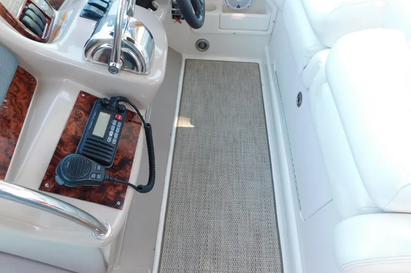 Slide: The Image of 2005 Sea Ray 320 Sundancer cockpit with radio and controls, featuring white seating and carpeted floor. - 31