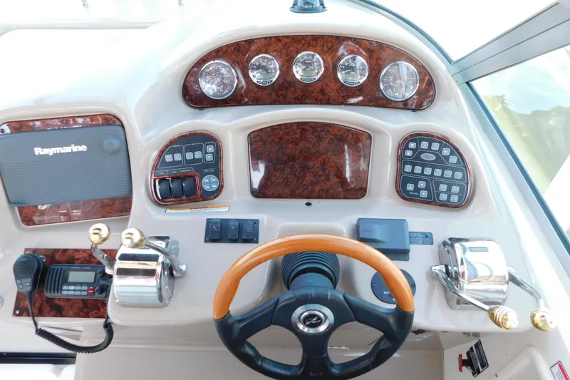 Slide: The Image of 2005 Sea Ray 320 Sundancer helm with Raymarine electronics and woodgrain dashboard. - 32