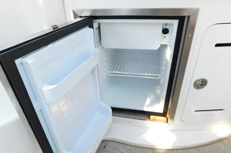 Slide: The Image of Open mini fridge on 2005 Sea Ray 320 Sundancer boat, showing interior shelves. - 44