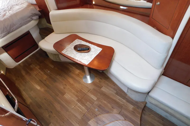Slide: The Image of 2005 Sea Ray 320 Sundancer interior with curved seating and wooden table. - 49