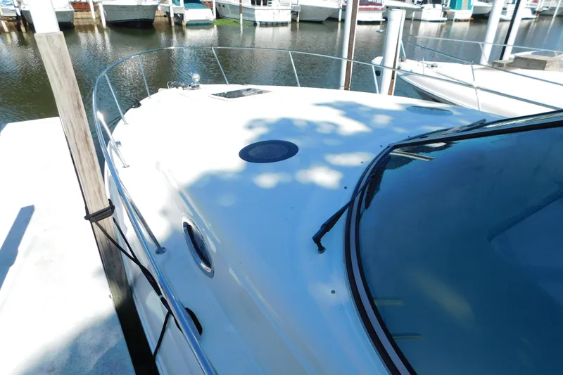 Slide: The Image of 2005 Sea Ray 320 Sundancer docked at marina, showcasing sleek design and white exterior. - 6