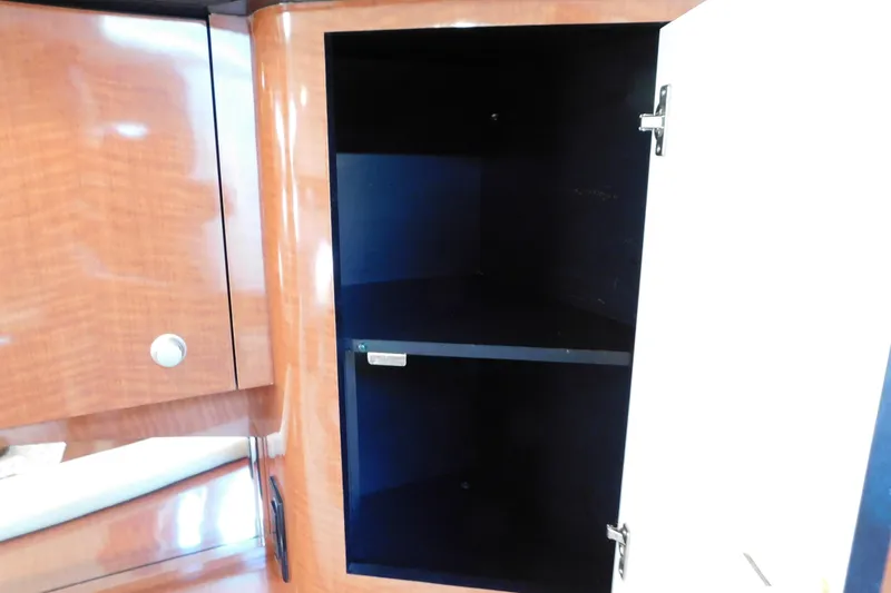 Slide: The Image of Open cabinet inside 2005 Sea Ray 320 Sundancer yacht, featuring wooden finish and shelving. - 65